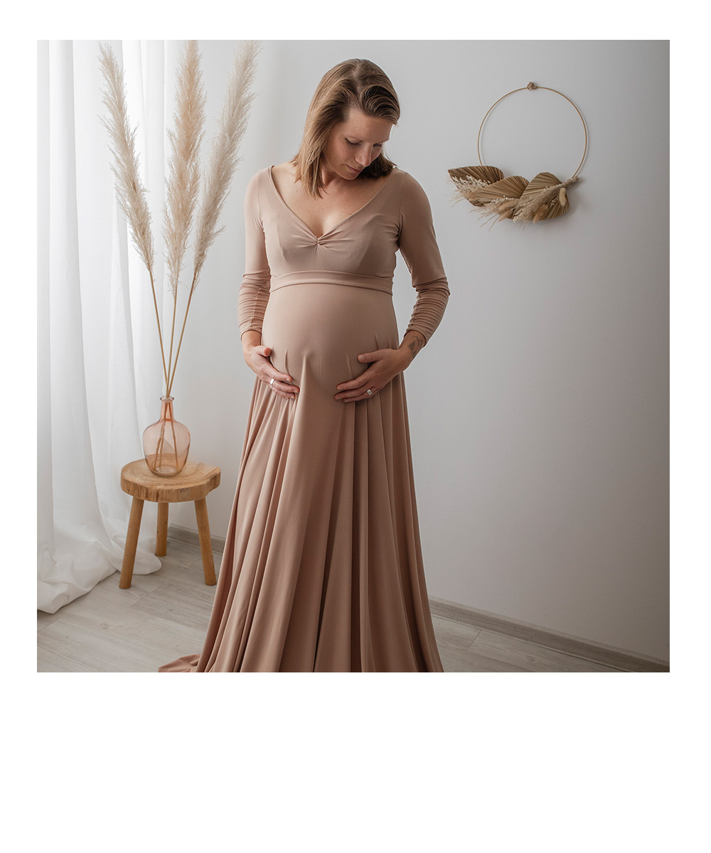 Schwarzweißbild, Frau leht an Wand, schaut auf ihren Babybauch