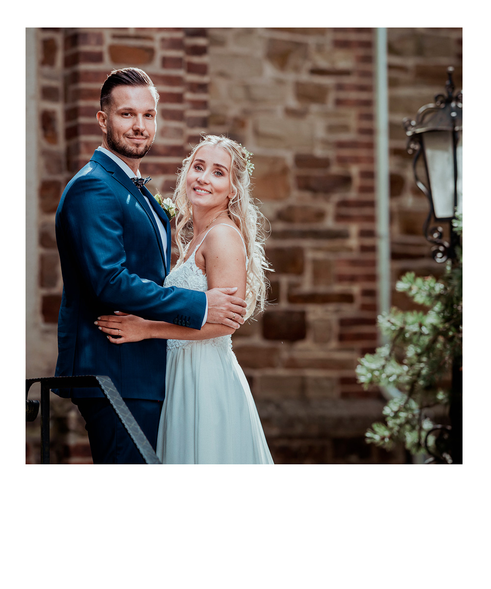 Frau sitzt im Schneidersitz auf einer Wiese und knuddelt ihren Hund